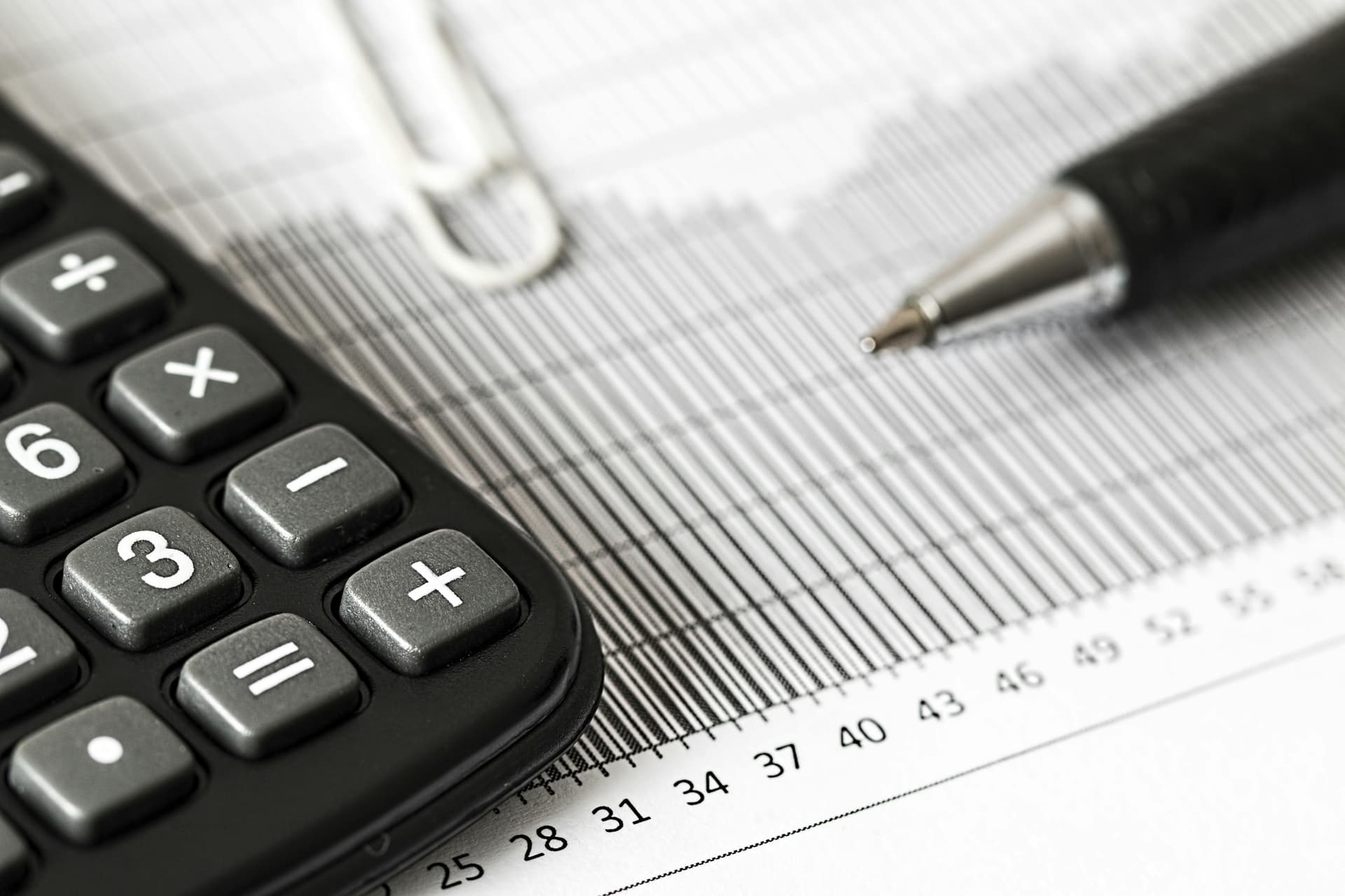 Office equipment like file, pen, calculator and a paper clip.