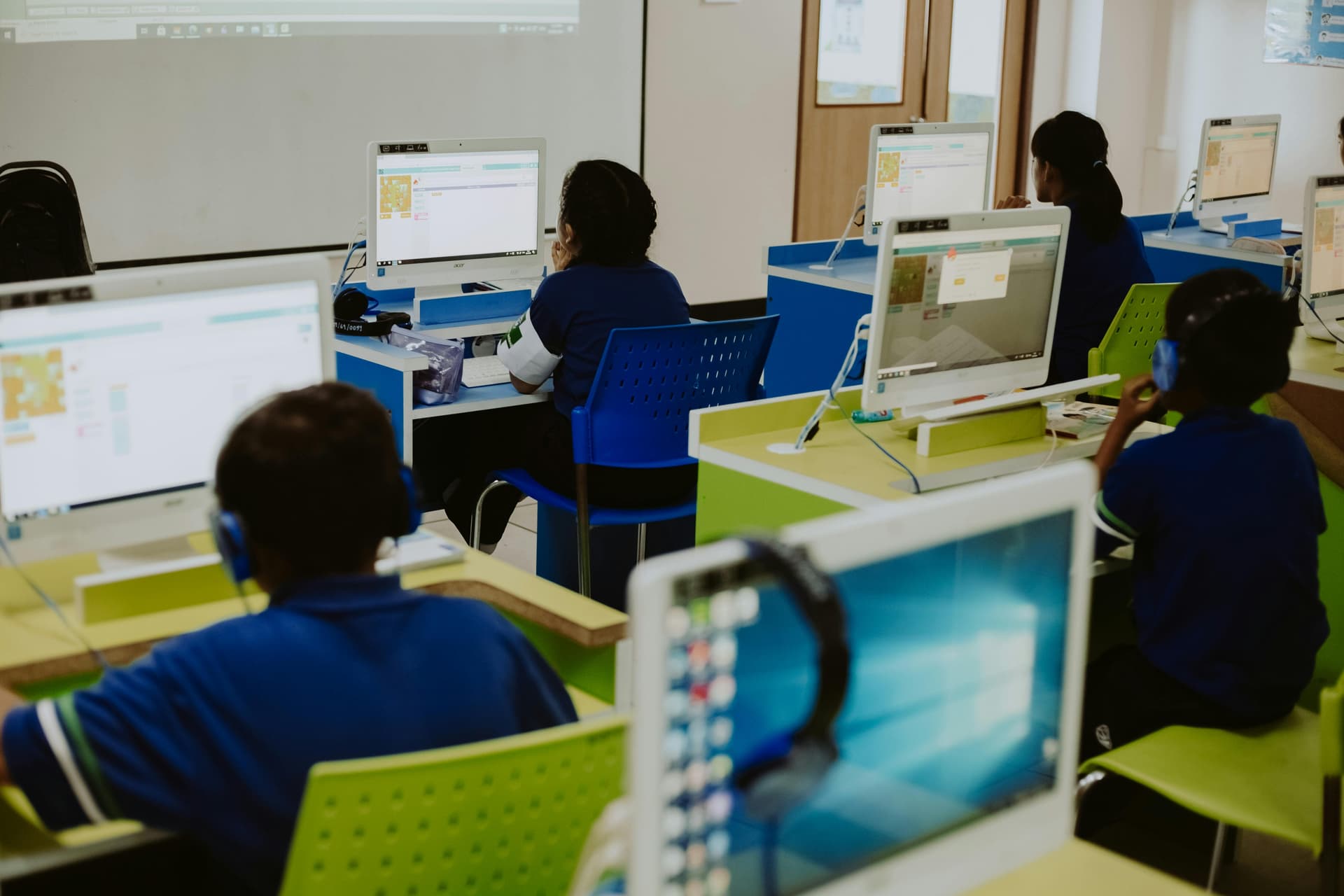 Students behind computer screens in a classroom.