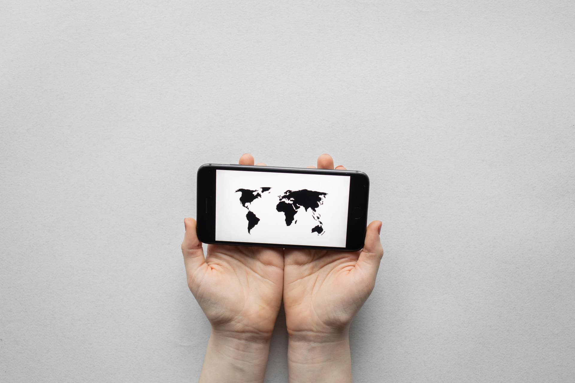 Hands holding a phone with a world map photo.